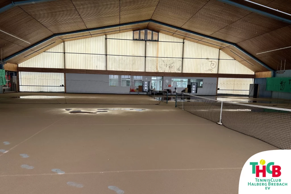 Bild unserer Tennishalle, der Teppichboden ist von einer Schmutzschicht überzogen, vereinzelt blieben Pfützen zurück